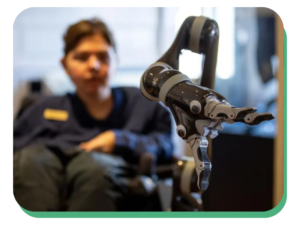 Wade Custer uses a new robotic arm on his wheelchair to pick up a book in the New Market Battlefield Visitor Center reaching for door